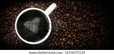 cup of hot coffee on coffee beans with a heart of foam