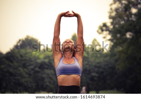 Sport woman play yoga in a green park, healthy or exercise or relaxing activity with hand up or stretch arms and legs