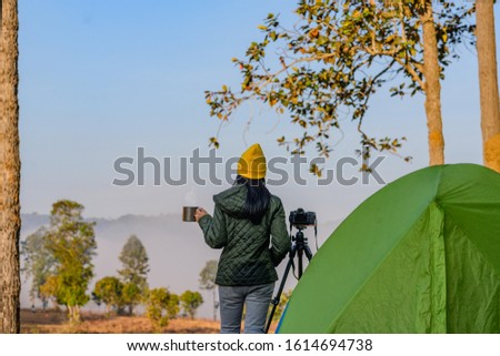 woman traveller photographer in motion of enjoy the morning nature of he foggy and mist flowing in front of the forest
