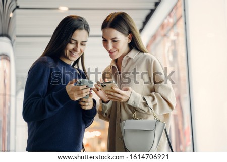 two girlfriends using their cellphone while exploring a new city at night. Two friends searching for information on their cellphone as they are exloring Beijing at night. Girlfriends pointing at an