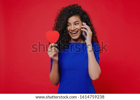 black woman with heart shaped valentine card talking on the phone on red background