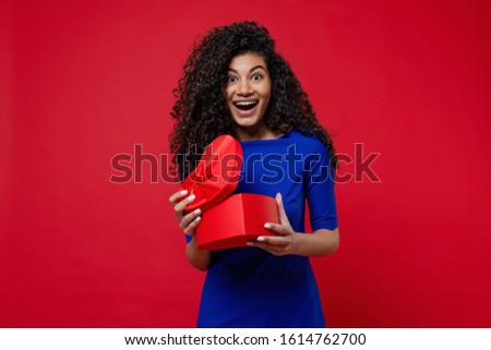 beautiful black woman opening heart shaped valentine gift box on red background