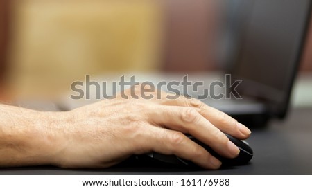 hand holding a mouse to a laptop, selective focus with boke