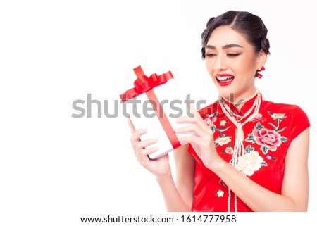 Beautiful young asian woman gets gift in Chinese New Year day. Charming beautiful girl get happiness when receive the gift, smiley face. She wear nice Chinese dress. She hold gift box. Studio on white