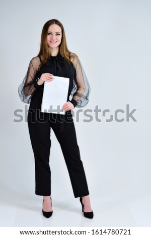 Concept portrait for a banner. Full-length photo of a pretty smiling brunette girl with a folder in her hands with excellent makeup in dark clothes is standing on a white background.