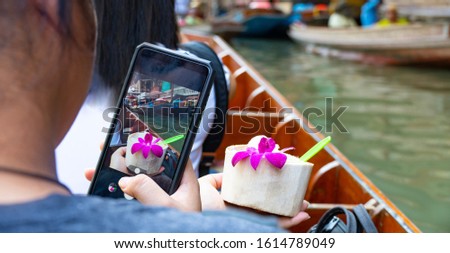 The girl is taking a picture,Fresh coconut ice cream ice cream ,On the wooden boat ,At Damnoen Saduak floating market