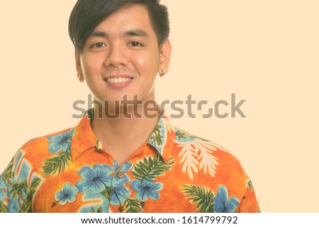 Portrait of happy young handsome Asian tourist man smiling