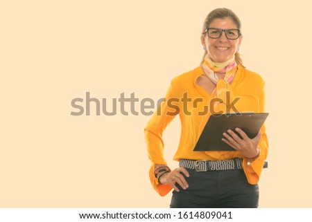 Studio shot of mature happy businesswoman smiling and holding clipboard