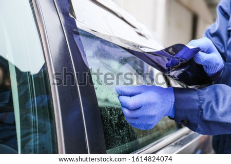 Male worker tinting car window, closeup