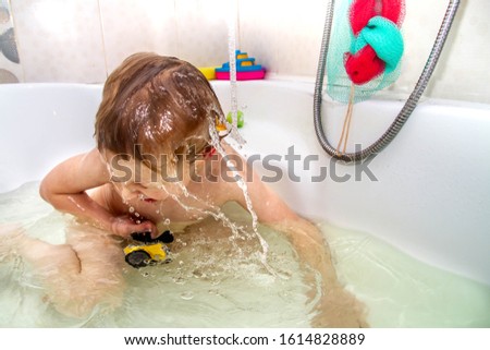 A boy bathes in water in the bathroom and shoots video with an action camera. The video camera in a protective does not pass water. Interests of modern children, to shoot a stream for social networks.