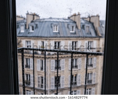 Picture of a window facing a beautiful Parisian building on a rainy day