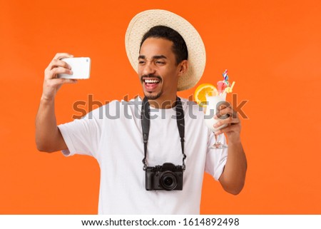 Charismatic, enthusiastic funny young african-american man smiling, cheering and drinking alcohol, taking selfie, photographing, holding camera, tourist on summer vacation