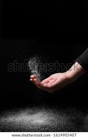 Creative image of hand scattering sugar powder on a dark background Royalty-Free Stock Photo #1614905407