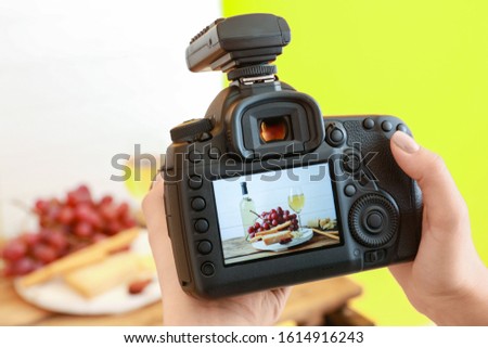 Female photographer taking picture of cheese and wine on table