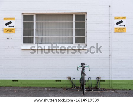 Bicycle, white brick wall, security camera warning signs