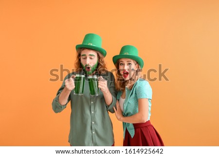 Young couple with beer on color background. St. Patrick's Day celebration