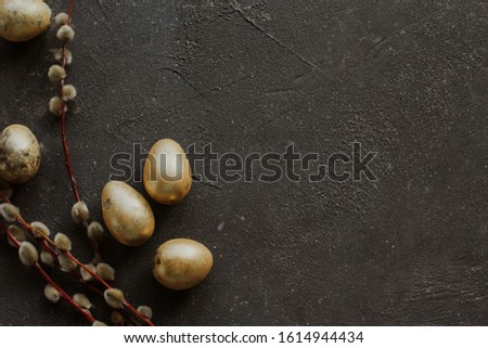 Golden easter quail eggs and willow branches on a dark gray rough background copy space.