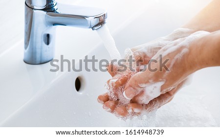 Woman use soap and washing hands under the water tap. Hygiene concept hand detail. Royalty-Free Stock Photo #1614948739