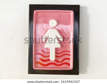 Restroom sign made of ceramic on the wall.