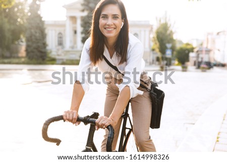 Cheerful young woman wearing summer clothes riding on a bicycle on a city street