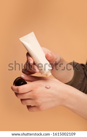 A young girl testing, applying  foundation on her hand. Trying, the tone, nuance of the powder by putting it on her arm. Selecting make-up Royalty-Free Stock Photo #1615002109