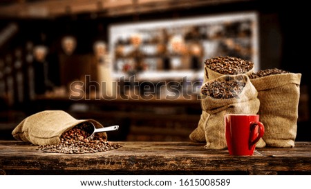 Fresh coffee beans in brown retro sacks and free space for your decoration.Dark interior of cafe and brown bar. Copy space and black shadows. 