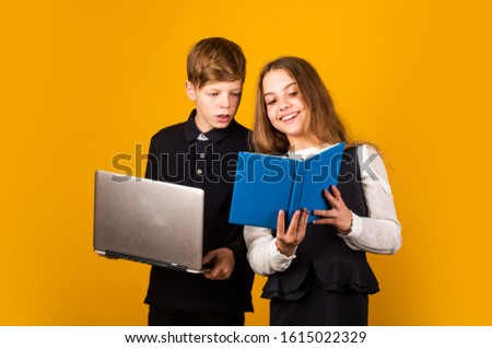 Opportunities for studying. Little children enjoy studying together yellow background. Small girl and boy hold book and laptop. Studying for exams. Studying and learning. Education and school.