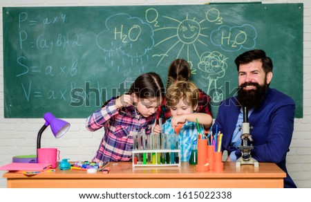 Discover and explore properties of substances together. Interests and topic club. Teacher and pupils test tubes in classroom. Older kids help younger. Chemistry themed club. School club education.