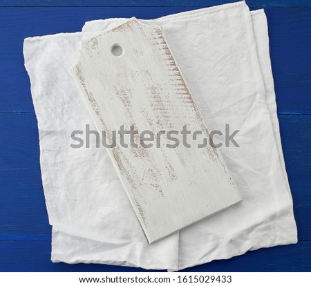 rectangular empty white kitchen cutting board and white textile towel on a blue wooden background from boards, top view