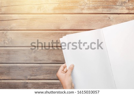 Hand holding a blank white hardcover book on background