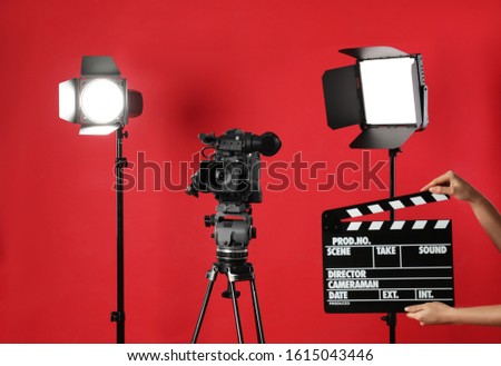 Woman with clapperboard near video camera in studio, closeup