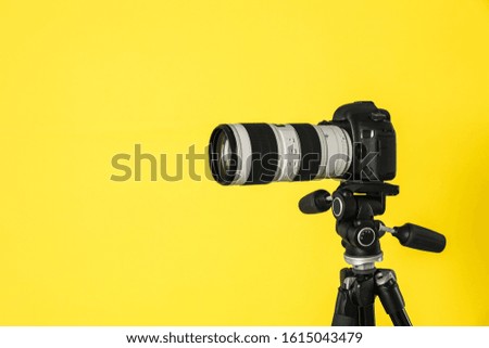 Modern professional video camera on yellow background
