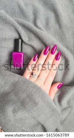 Female hand with long nails and pink fuchsia bottle manicure with nail polish