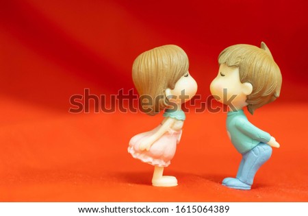 The Miniature Couple dolls Boy and Girl Romantic Kiss on Red Background for valentine's Day Concept
