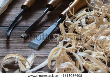 Instruments for wood carving with wood shavings at brown rustic old table. Wood craft background