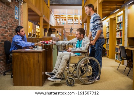 Side view of a male student in wheelchair at the counter in college library