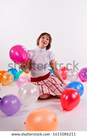 blonde girl on a white background in the studio in a white blouse and skirt plays with balloons