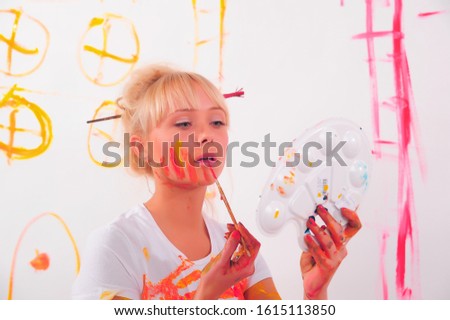 Beautiful young woman painter with paint brush in hands,