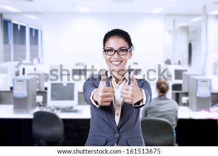 Beautiful businesswoman showing two thumbs up in the office