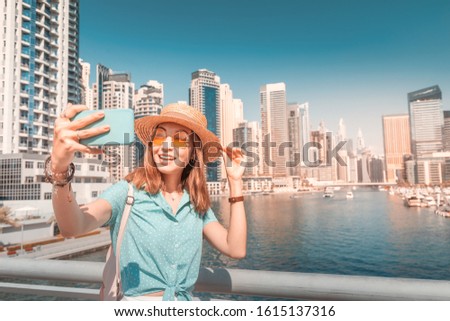 Happy Asian tourist girl takes selfie photos in popular Marina district in Dubai for her social media and blog