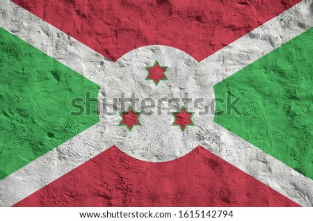 Burundi flag depicted in bright paint colors on old relief plastering wall. Textured banner on rough background