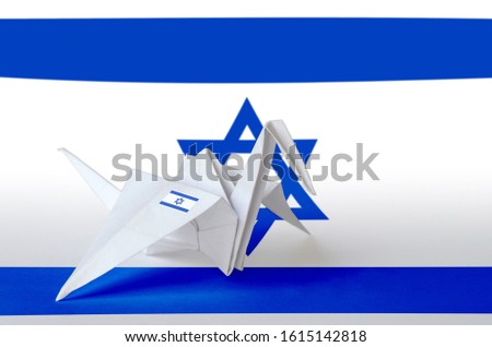 Israel flag depicted on paper origami crane wing. Handmade arts concept