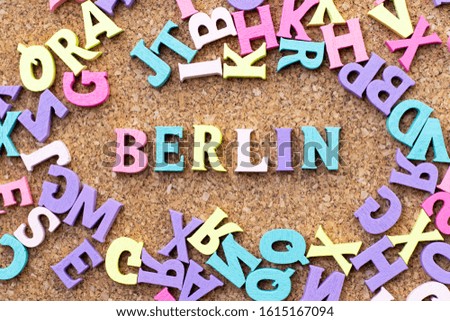 Color alphabet in word Berlin with another letter as frame on cork board background