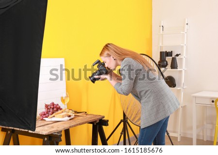 Young woman taking picture of cheese and wine in professional studio