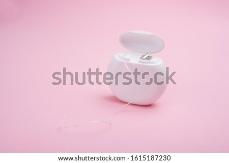 Dental floss on a pink background. Copy space.