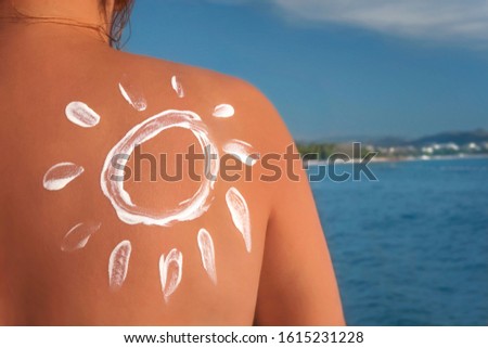 Woman applying sun cream on tanned shoulder in form of the sun. Sun protection. Skin and Body Care. 