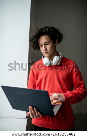 Casual guy with headphones looking at laptop display while searching for information in the net