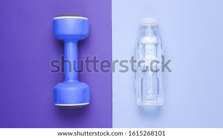 Minimalistic fitness concept. Dumbbell, bottle of water on colored background. Top view