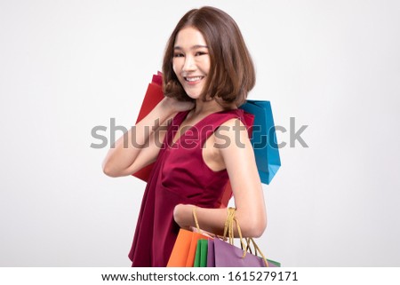 Shopping Asian woman with short hairs smile wearing red dress Holding Shopping bags,Cheerful and Happiness enjoy shopping in black friday sale,Isolated on gray background