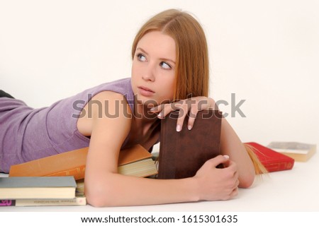 thinking young woman lying on the floor with book